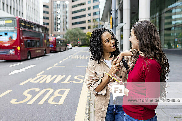 Woman having conversation with friend at bus stop