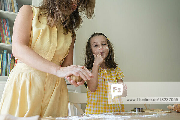 Cute girl preparing cookies with mother at home