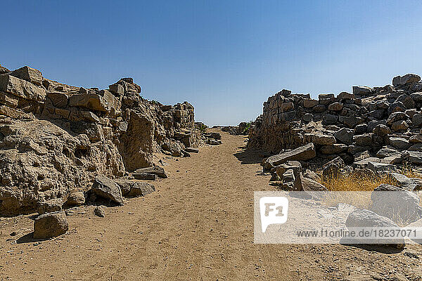 Empty dirt road amidst rocks under blue sky at Al-Ukhdud Archaeological Site in Najran  Saudi Arabia