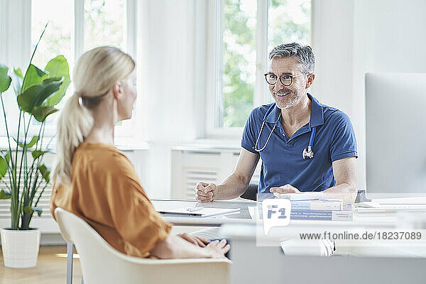Happy doctor having discussion with patient at medical practice