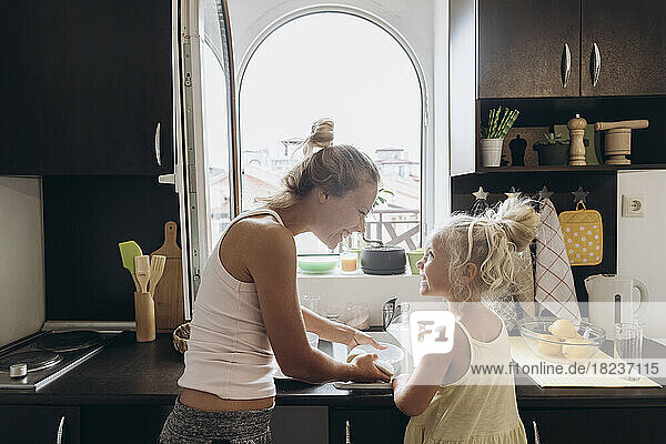 Frau und Tochter haben Spaß beim Geschirrspülen in der Küche