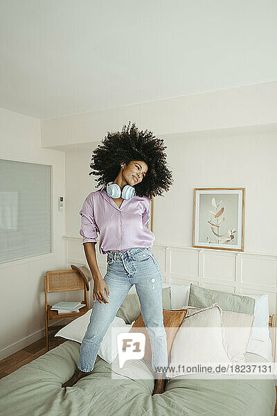 Young Afro woman on bed in bedroom at home
