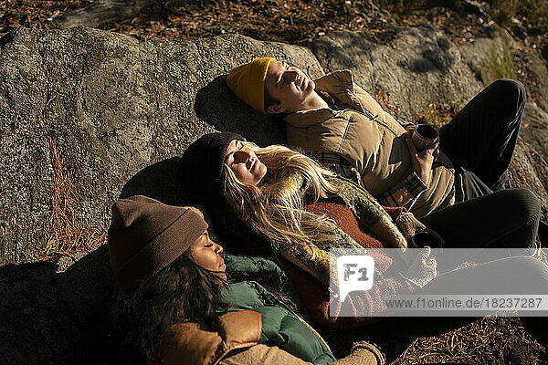 Hohe Winkel Ansicht der männlichen und weiblichen Freunde entspannen auf Felsen während des sonnigen Tages