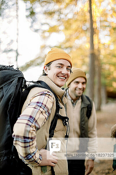 Seitenansicht eines glücklichen jungen Mannes mit Rucksack durch einen männlichen Freund