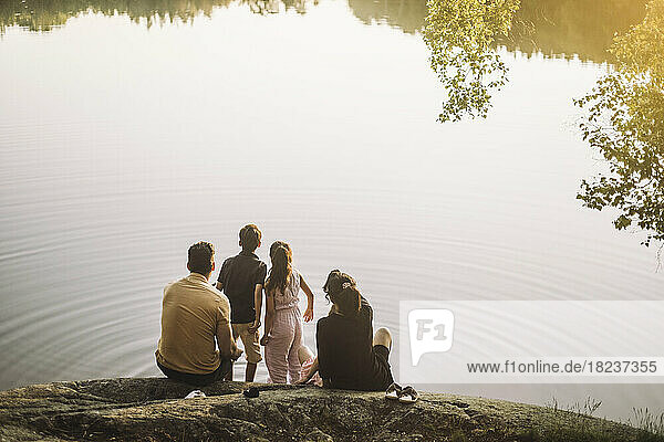 Familie schaut auf den See  während sie beim Picknick auf einem Felsen sitzt
