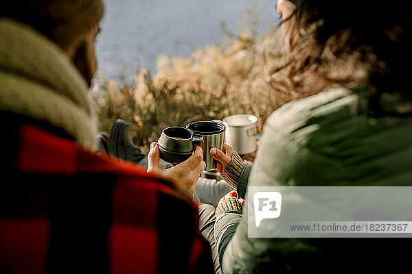 Friends toasting coffee during camping in forest