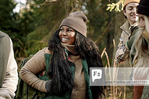 Happy young woman wearing warm clothing while looking at friend