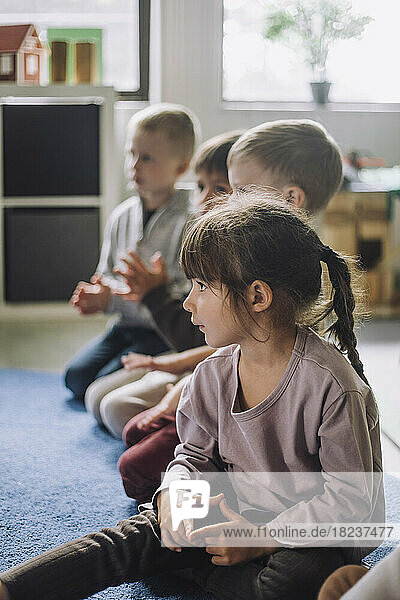 Multiracial children sitting on carpet in kindergarten