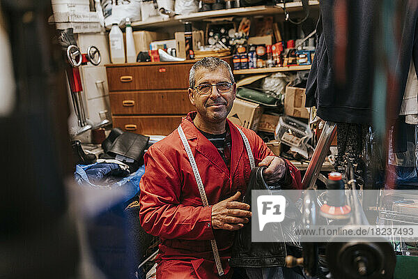 Porträt eines lächelnden Schlossers mit Leder  der in einer Reparaturwerkstatt arbeitet