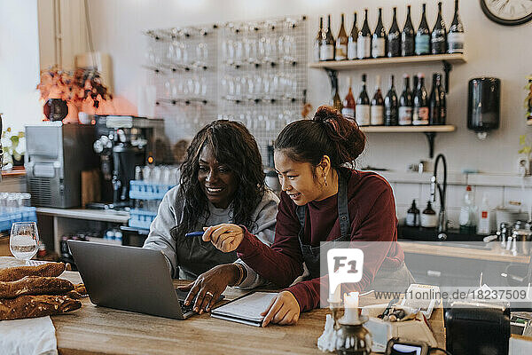 Unternehmerinnen  die in einem Café über einen Laptop diskutieren