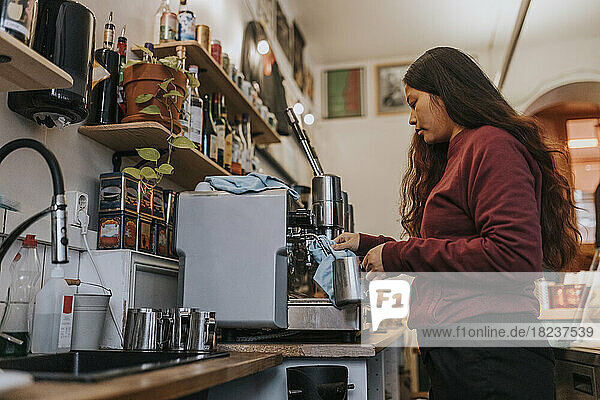 Seitenansicht einer Unternehmerin beim Kaffeekochen in einem Café