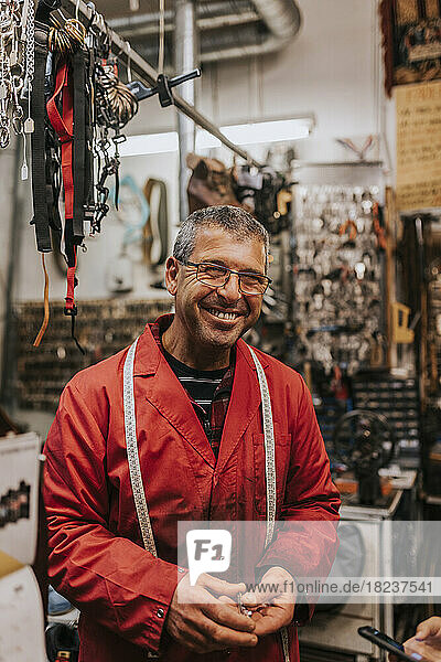 Porträt eines fröhlichen männlichen Schlossers mit Brille in einer Werkstatt