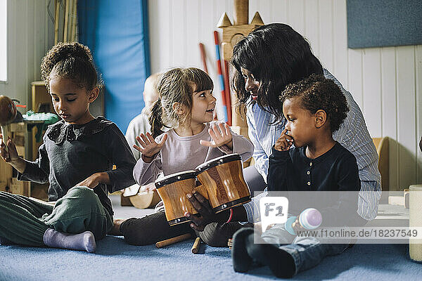Lehrerin bringt Mädchen in einer Kindertagesstätte das Schlagzeugspielen bei