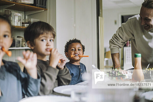 Multiracial male and female students eating carrots for breakfast in day care center