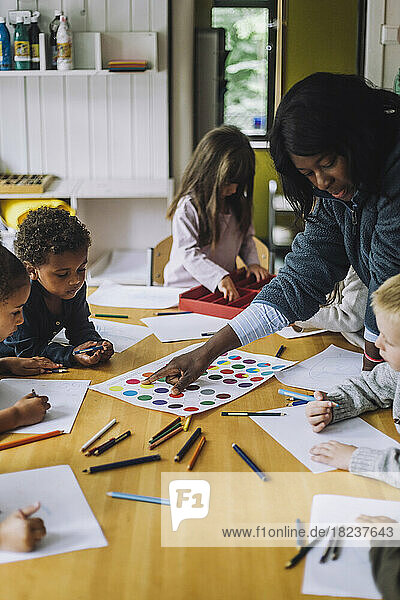 Lehrerin  die Schülern im Kindergarten das Erkennen von Farben beibringt