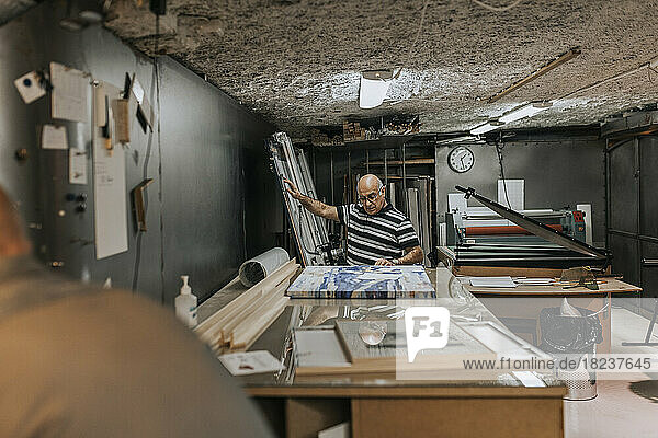 Senior craftsman examining picture frame at workbench
