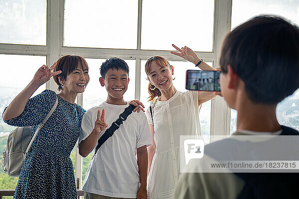 A boy using his mobile phone to take a picture of three Japanese people  a 13 year old boy  his mother and a friend.