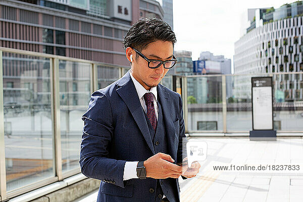 A young businessman in the city  on the move  a man outdoors in a suit looking at his mobile phone.