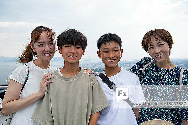 Four Japanese people on a outing  two mature women and two 13 year old boys  in a row  on a viewing platform.