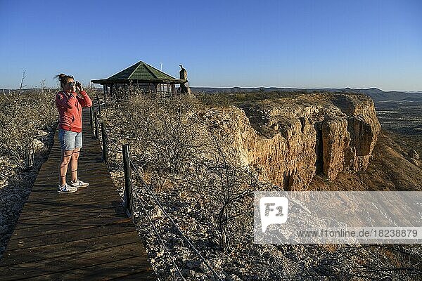 Touristin blickt durch Fernglas  Aussichtspunkt am Eagles Nest  Restaurant auf einem Tafelberg nahe der Vinkerklip Lodge  Fingerklippe  Ugab-Tal  Region Kunene  Namibia  Afrika