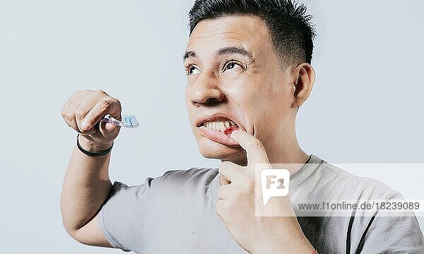 Mann hält Zahnbürste mit Zahnfleischschmerzen isoliert  Menschen halten Zahnbürste mit Zahnfleischproblem isoliert. Junger Mann mit Zahnfleischentzündung hält Zahnbürste  Menschen halten Zahnbürste mit Zahnfleischschmerzen