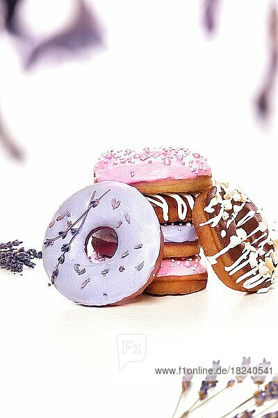Süße mehrfarbige Donuts auf weißem Hintergrund mit Lavendelblüten