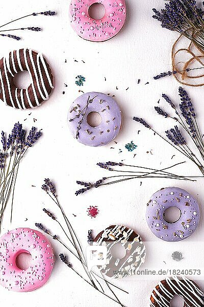 Süße mehrfarbige Donuts auf weißem Hintergrund mit Lavendelblüten