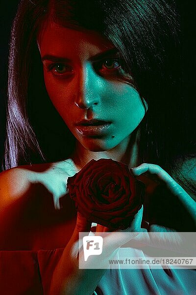 Schönes Mädchen mit einer Rose in der Hand. Die Schönheit des Gesichts. Porträtaufnahme im Studio mit Farbfiltern