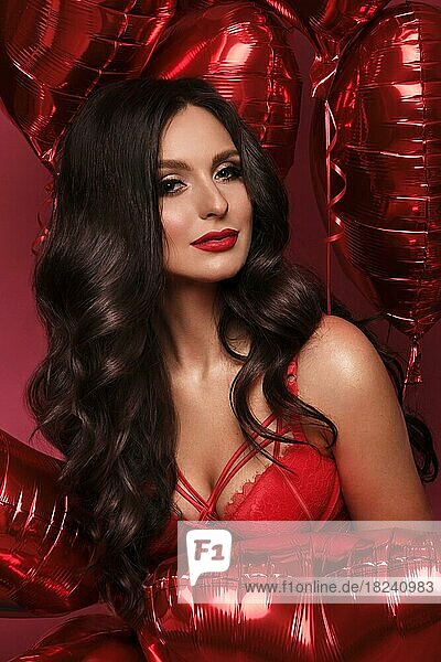 Sexy woman in red lace lingerie and balloons with hearts posing in the studio on Valentine's Day