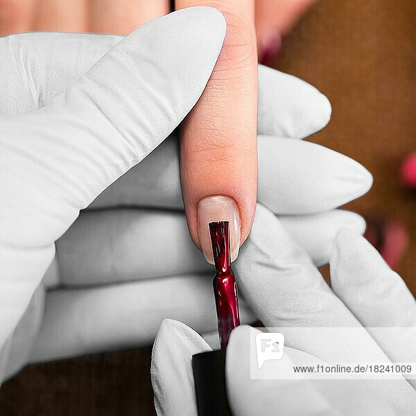 Closeup Fingernagelpflege von Maniküre-Spezialist in Schönheitssalon. Maniküre malt Nägel mit rotem Nagellack