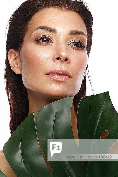 Schöne frische Frau mit perfekter Haut  natürliches Make-up und grüne Blätter. Schönes Gesicht. Foto im Studio aufgenommen