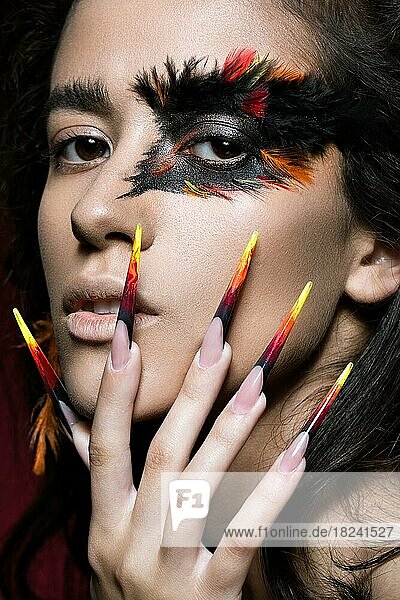 Beautiful girl in the image of the Phoenix bird with creative makeup and long nails. Manicure design. The beauty of the face. Photos shot in studio