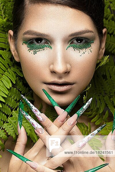 Schönes Mädchen mit Kunst-Make-up  Farnblättern und langen Nägeln. Maniküre Design. Die Schönheit des Gesichts. Fotos im Studio aufgenommen