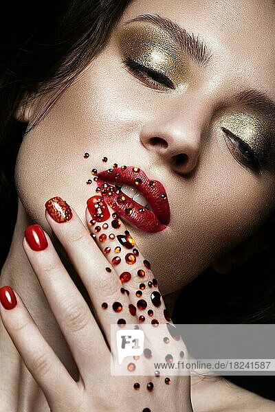 Beautiful girl with evening make-up  red lips in rhinestones and design manicure nails. beauty face. Photos shot in studio