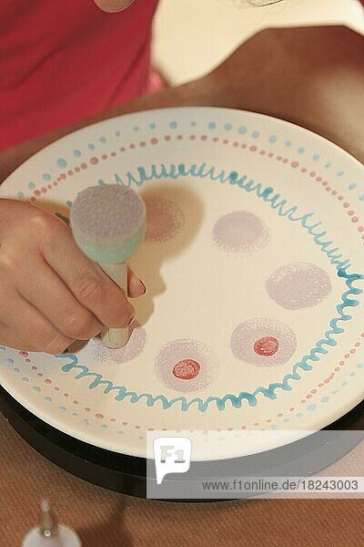 Ein Kind bemalt und verziert einen Teller