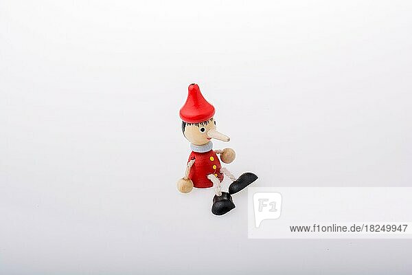 Hölzerne Pinocchio-Puppe mit langer Nase auf weißem Hintergrund