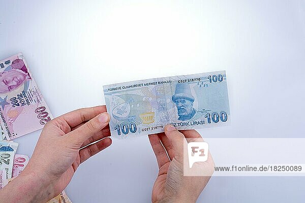 Hand hält türkische Lira-Banknote auf weißem Hintergrund