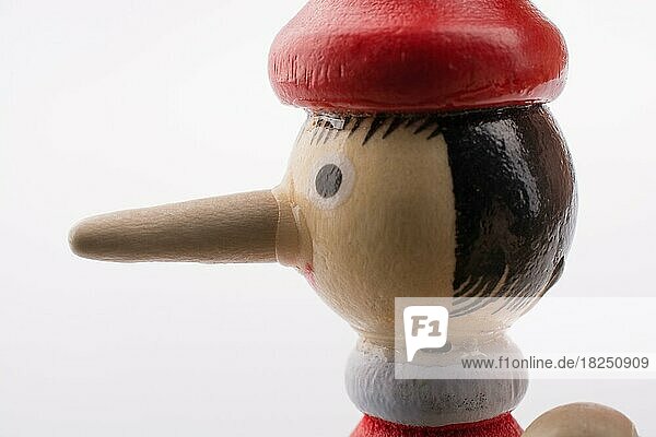 Hölzerne Pinocchio-Puppe mit langer Nase auf weißem Hintergrund