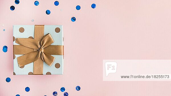 Eingepacktes Geschenk mit brauner Schleife und Band auf pastellrosa Kulisse. Auflösung und hohe Qualität schönes Foto
