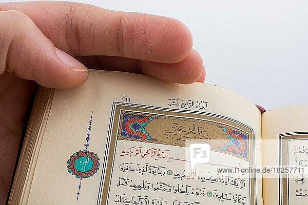 Hand hält den Heiligen Koran auf weißem Hintergrund
