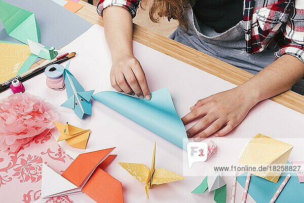 Weibliche Künstlerin faltet Origami-Papier und macht schönes Handwerk