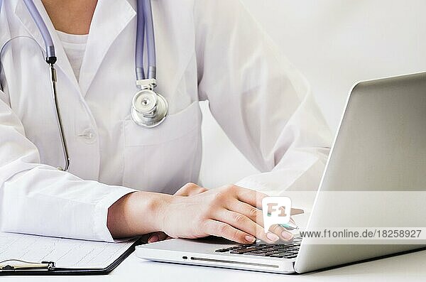 Female doctor with stethoscope around her neck using laptop desk