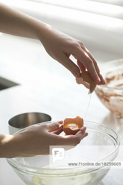 female hands cracking an egg to separate yolk from egg white