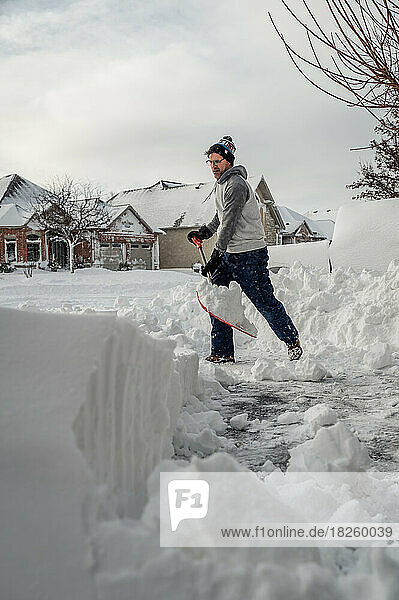 Man shoveling snow off of his driveway after a winter storm.