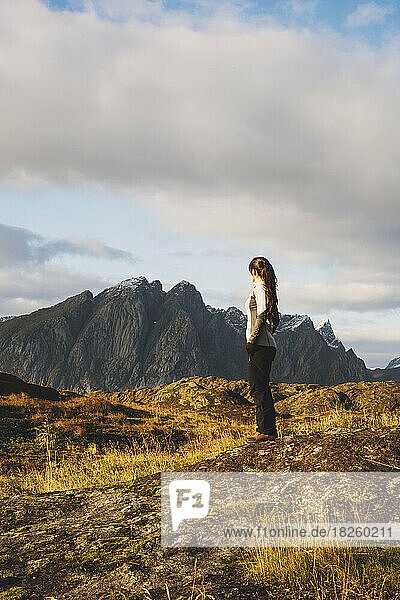 Lonely female hiker looking at norvegian mountains