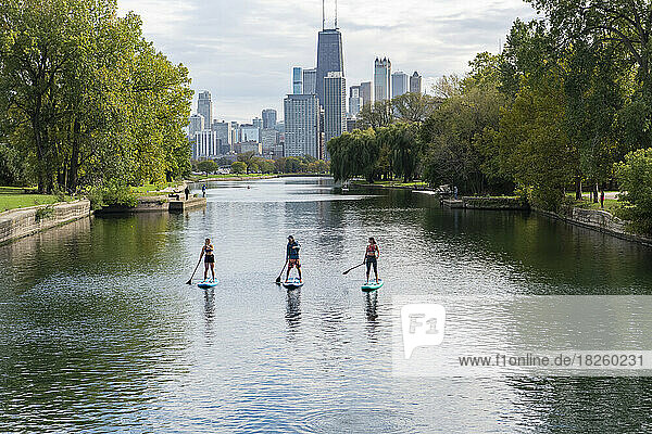 friends paddleboarding in river with city in background