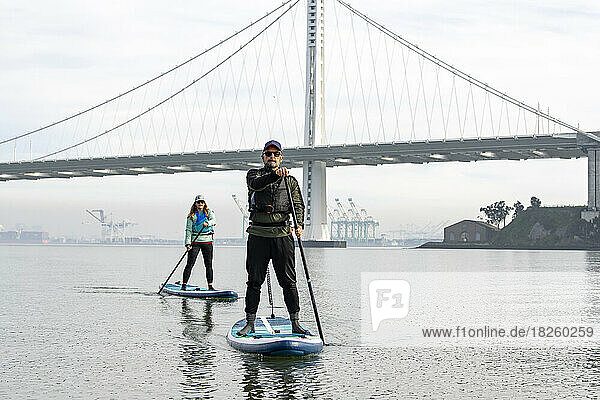 friends paddleboarding while Oakland Bay Bridge in background