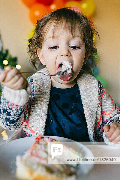 Little girl eating a piece of birthday cake
