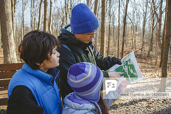 A father and children stand in forest in winter looking at map