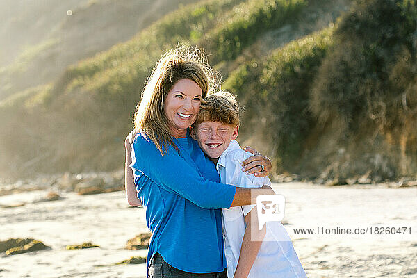 Mother Tightly Embraces Tween Son At The Beach